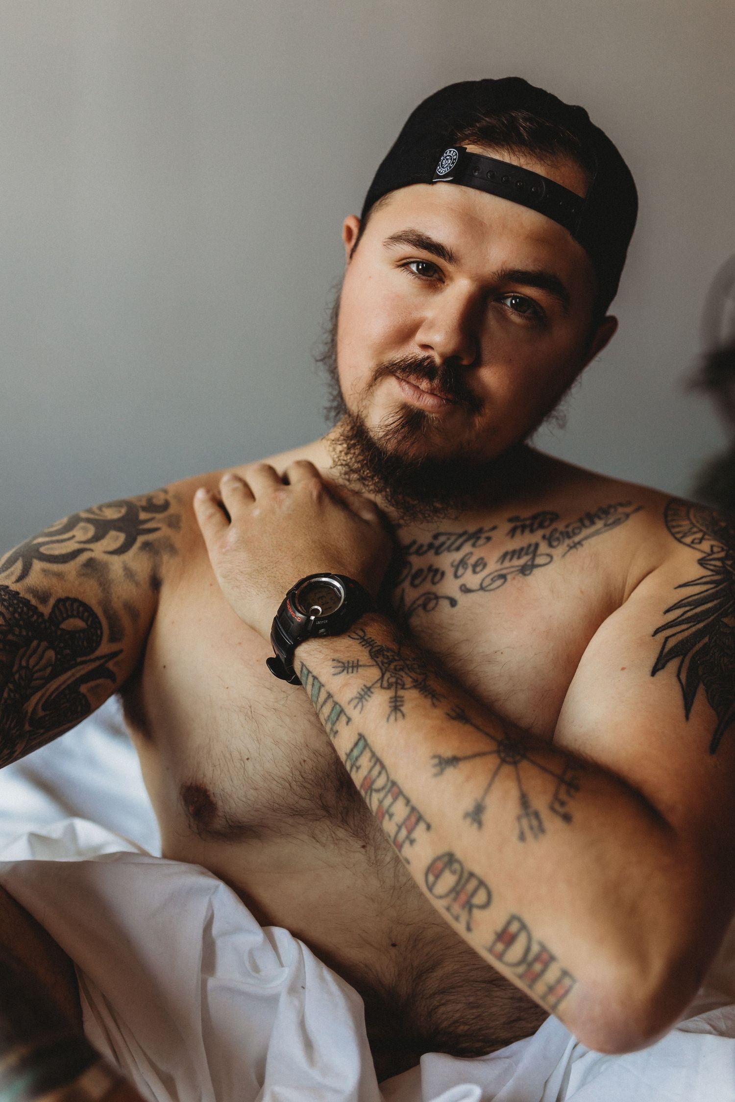 Intimate portrait showing detailed tattoo work in soft natural lighting.