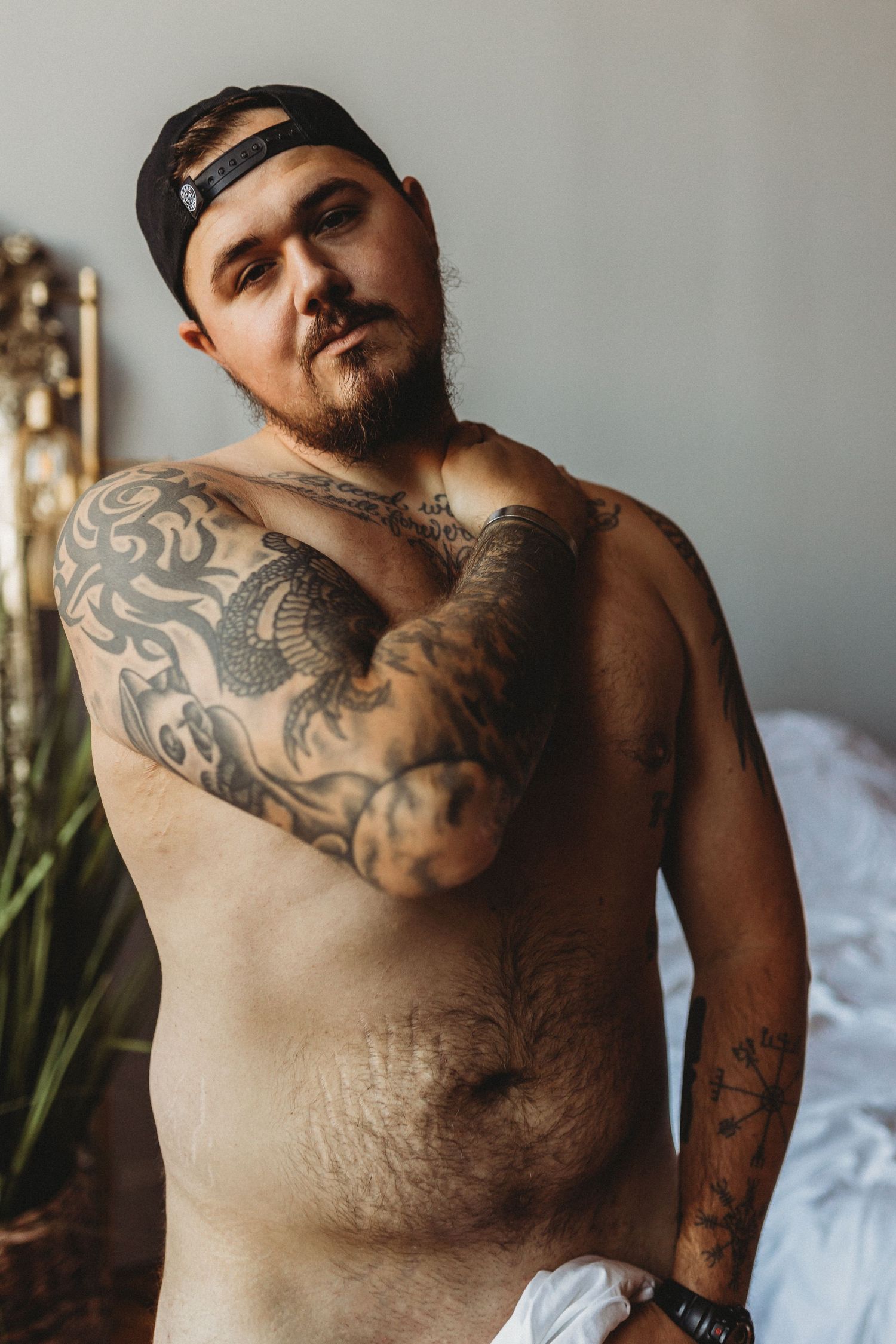 Body positive boudoir photography with natural lighting and white sheets.
