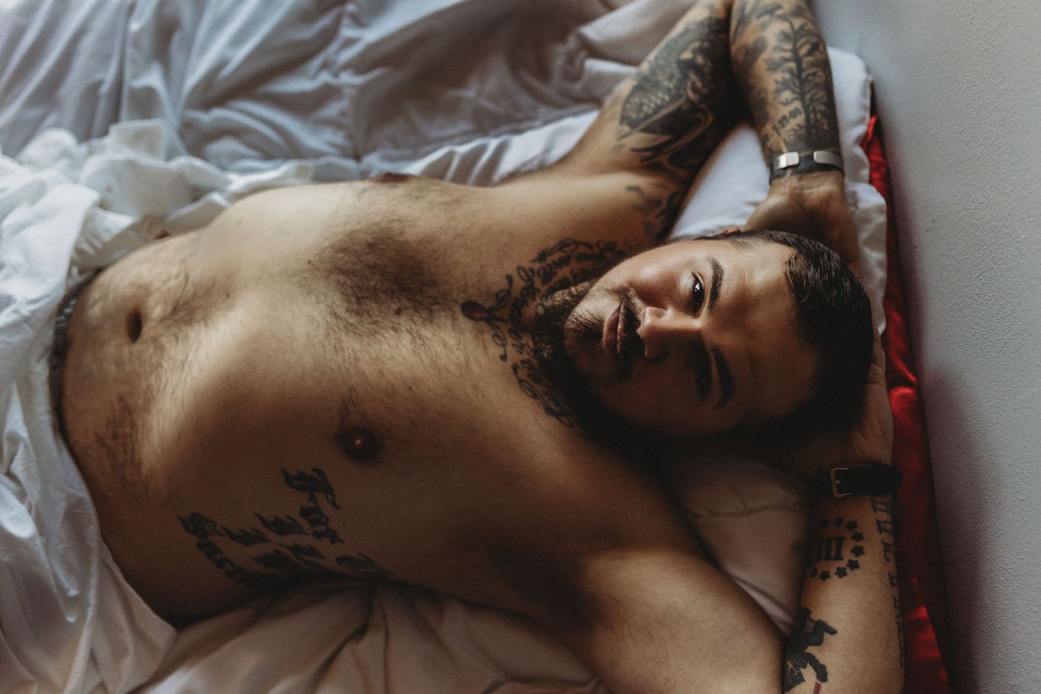 Intimate bedroom portrait with artistic lighting and white sheets.