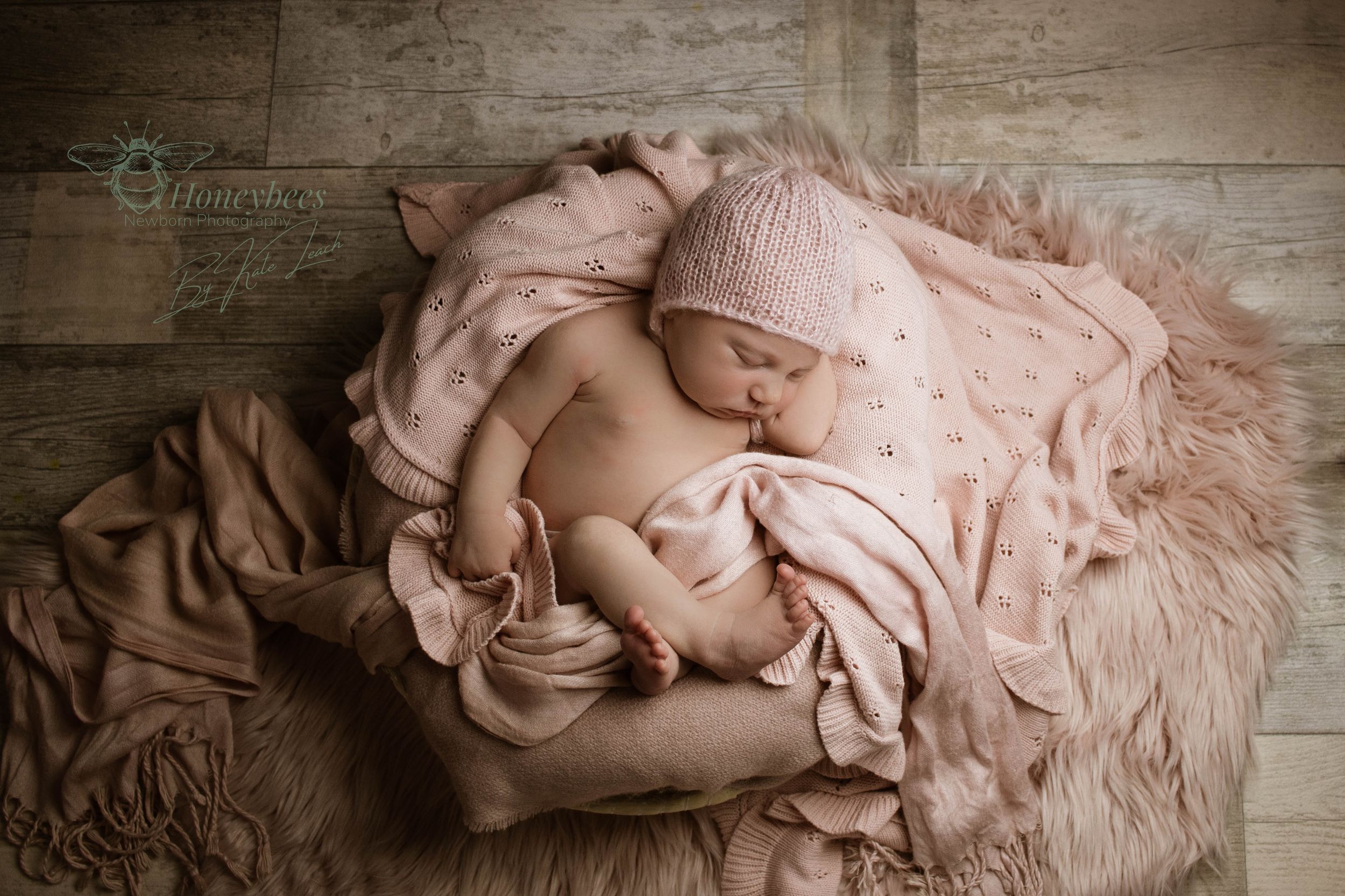 Newborn photography in York baby wrapped in blankets asleep in a pillow on a wooden floor
