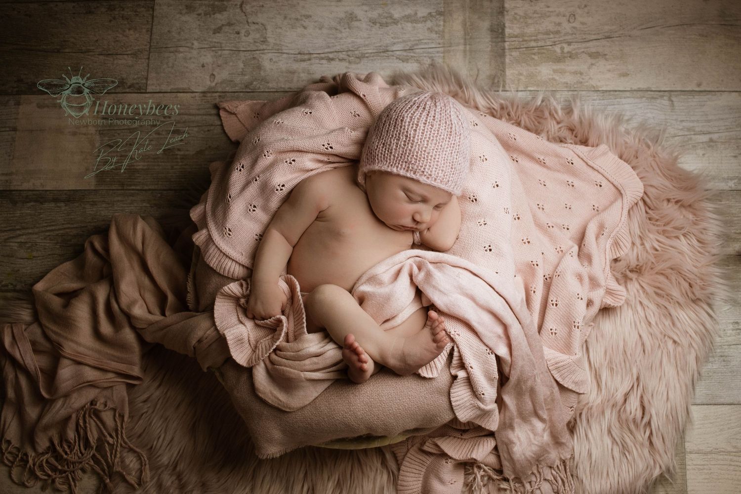 Newborn photography in York baby wrapped in blankets asleep in a pillow on a wooden floor
