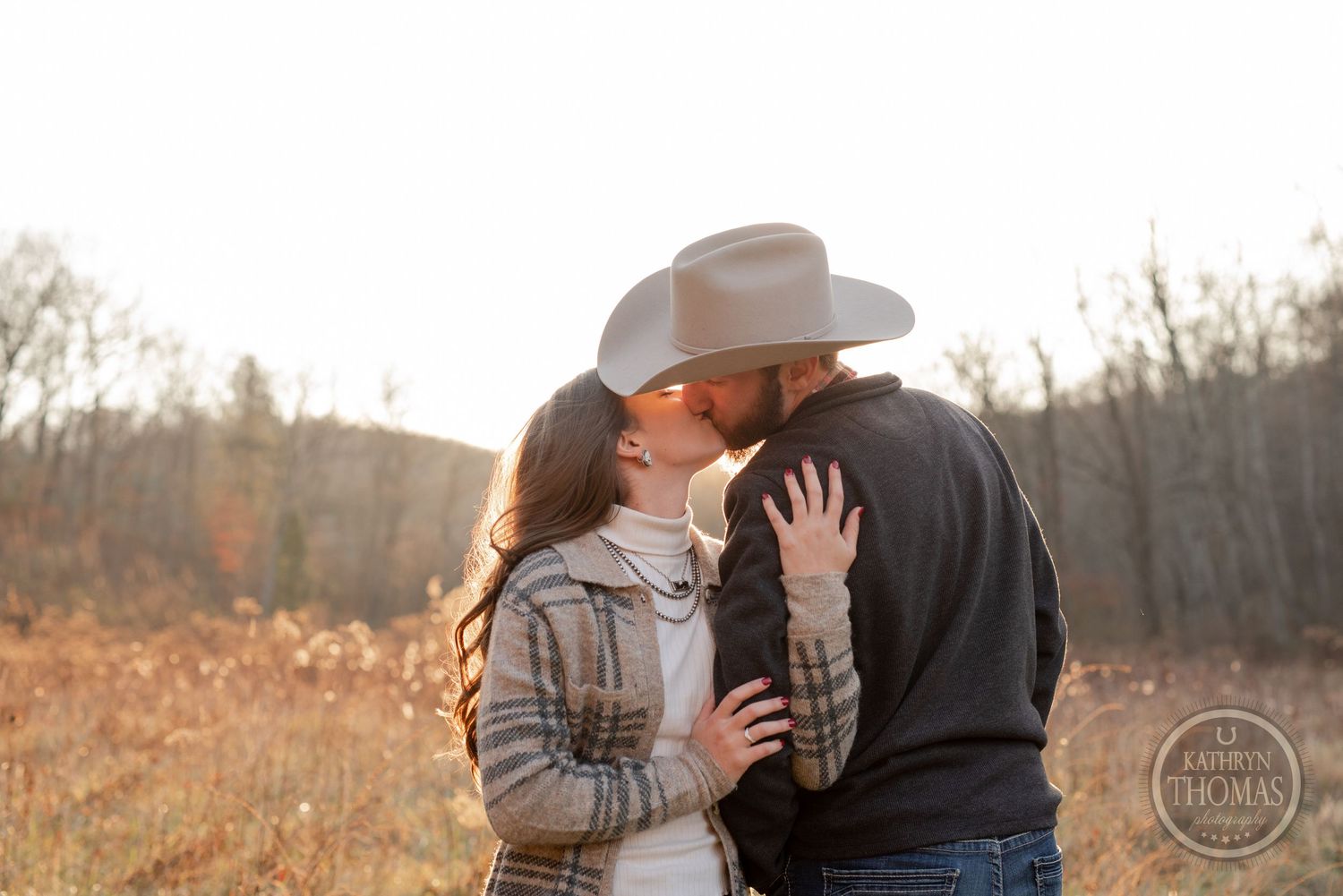 A romantic outdoor photoshoot in fall features a couple embracing in golden light.
