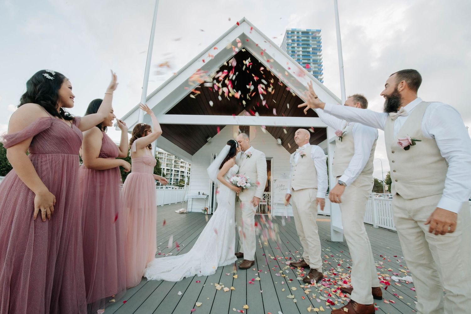 Wedding party creates arch with sparklers as couple exits under white gazebo.