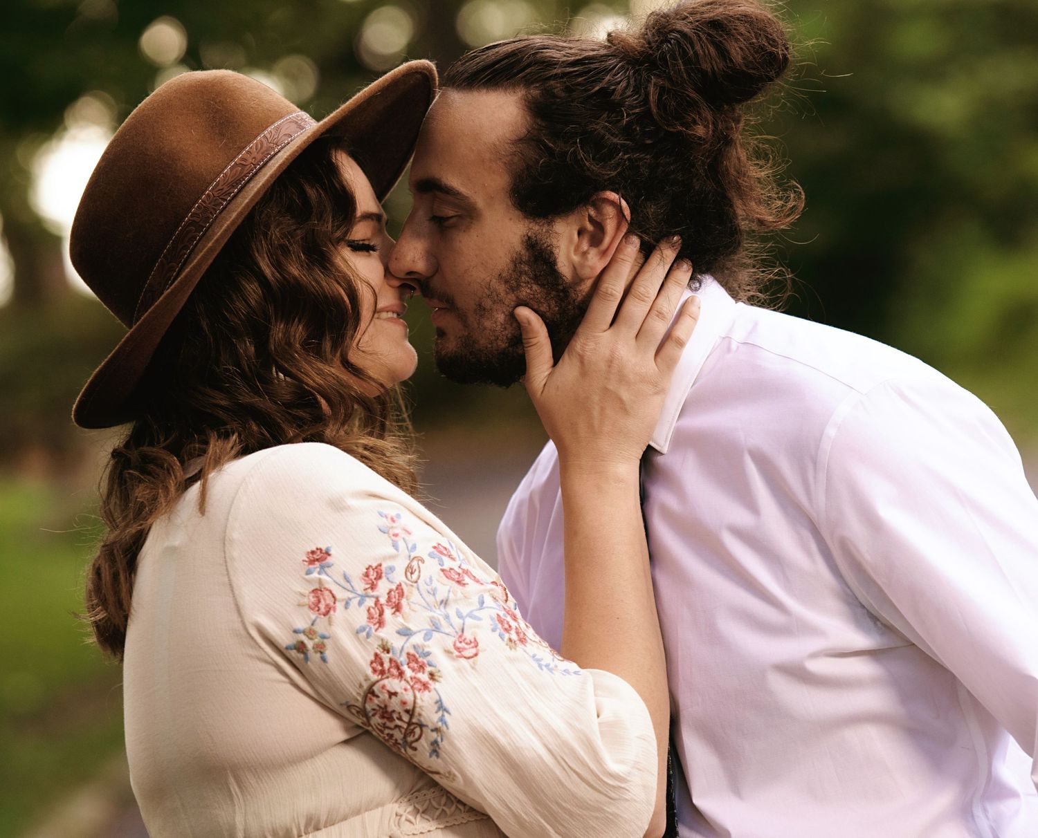 Romantic couple in white and brown clothing share intimate moment in summer garden.