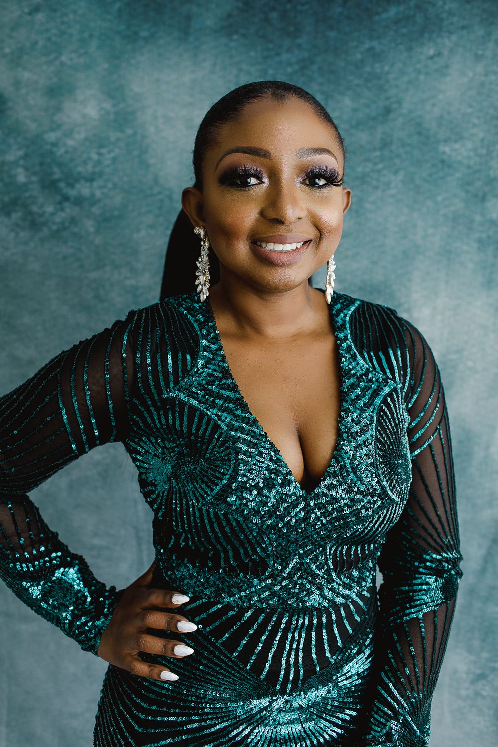 Close-up portrait in sparkling teal gown with statement earrings.