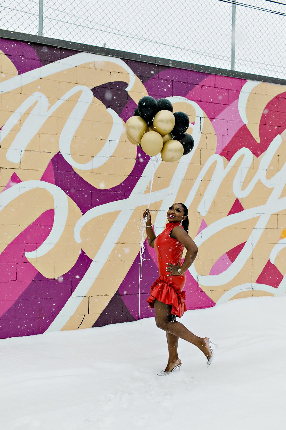 Festive pose with balloons against colorful mural wall.