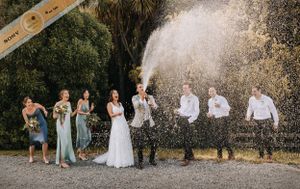 Bronze award photo of groom spraying champagne really high in the air and the wedding party looking shocked and laughing