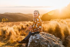 Young girl sitting on rock at sunset in Port Hill Christchurch