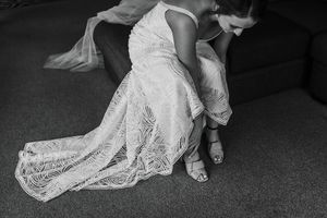 black and white photo of bride putting on shoes and dress trailing behind