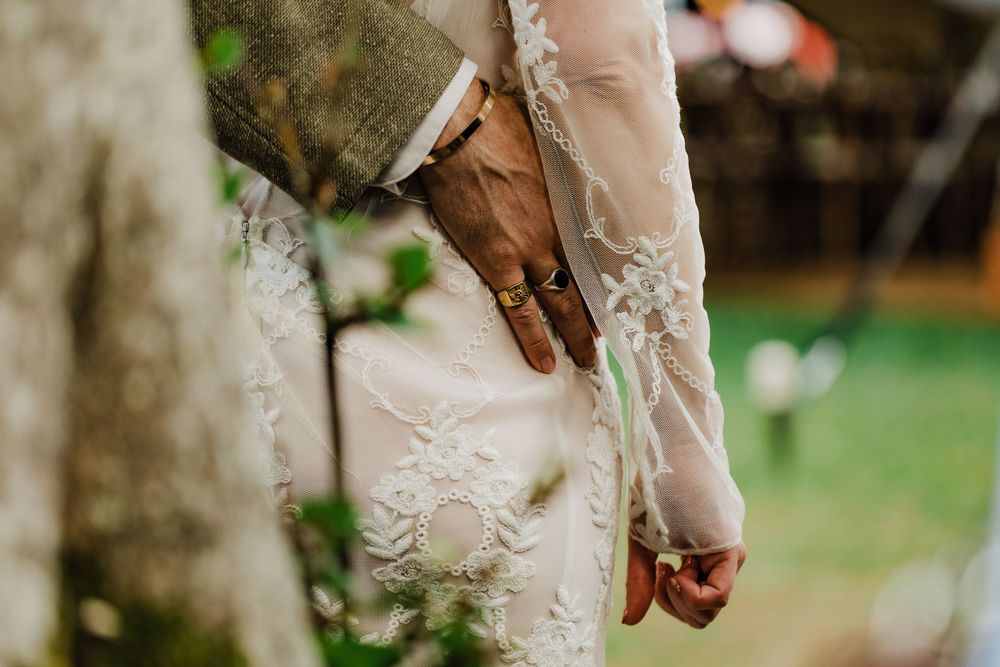 Detailed shot of intricate lace sleeve patterns on a wedding dress against a natural background.