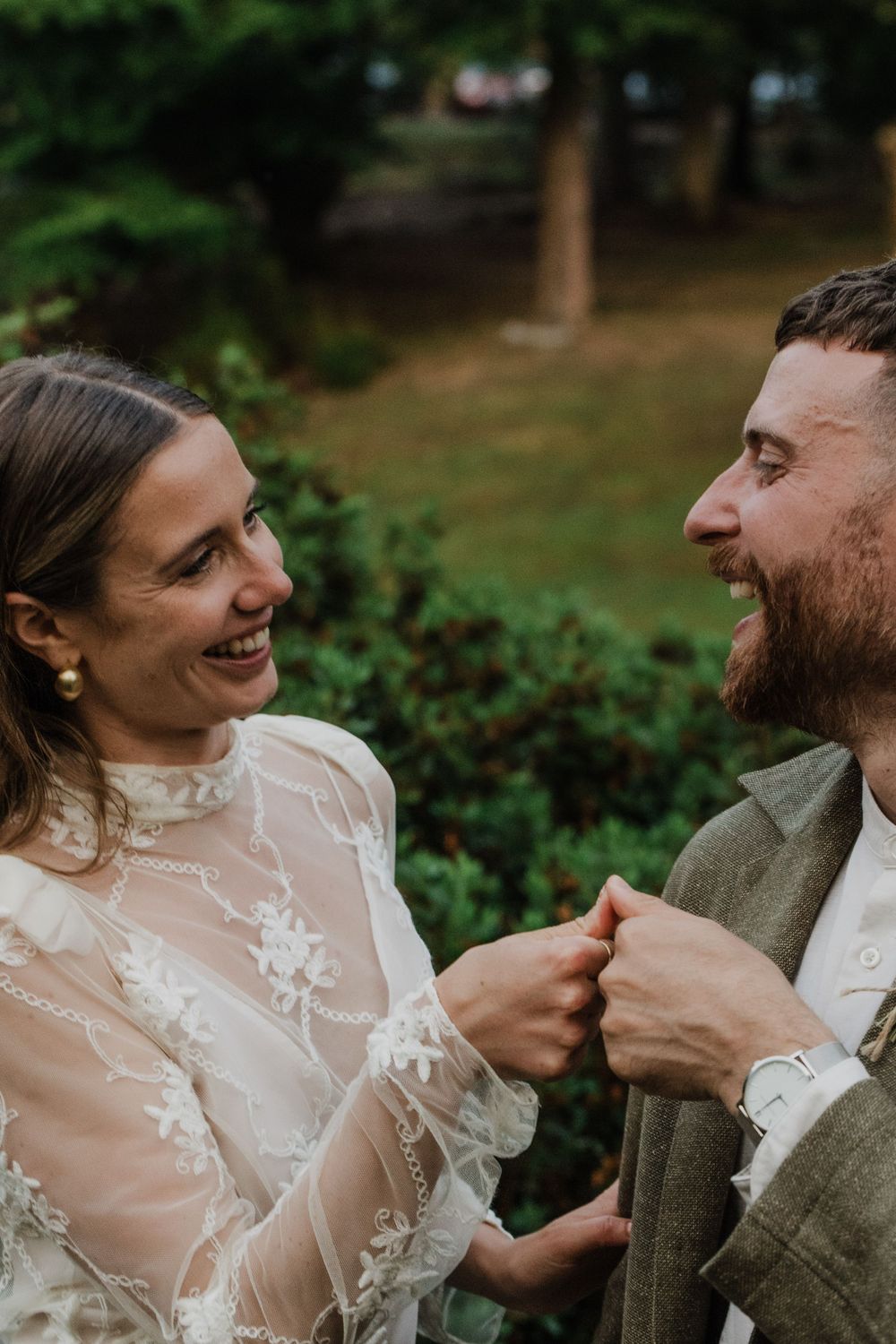 A candid moment of laughter shared between newlyweds in an outdoor setting.