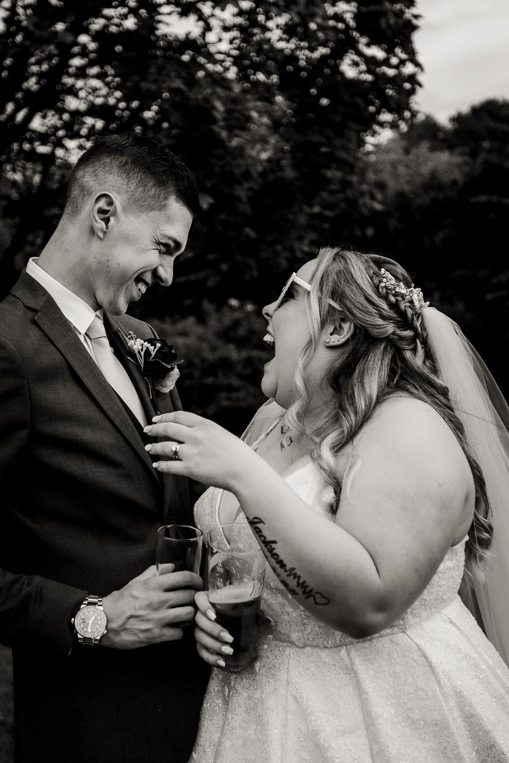 A candid black and white moment of shared laughter during a wedding celebration.