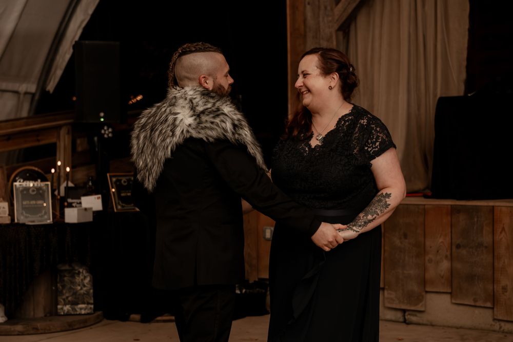 Couple in black formal wear sharing a joyful moment at wedding reception.