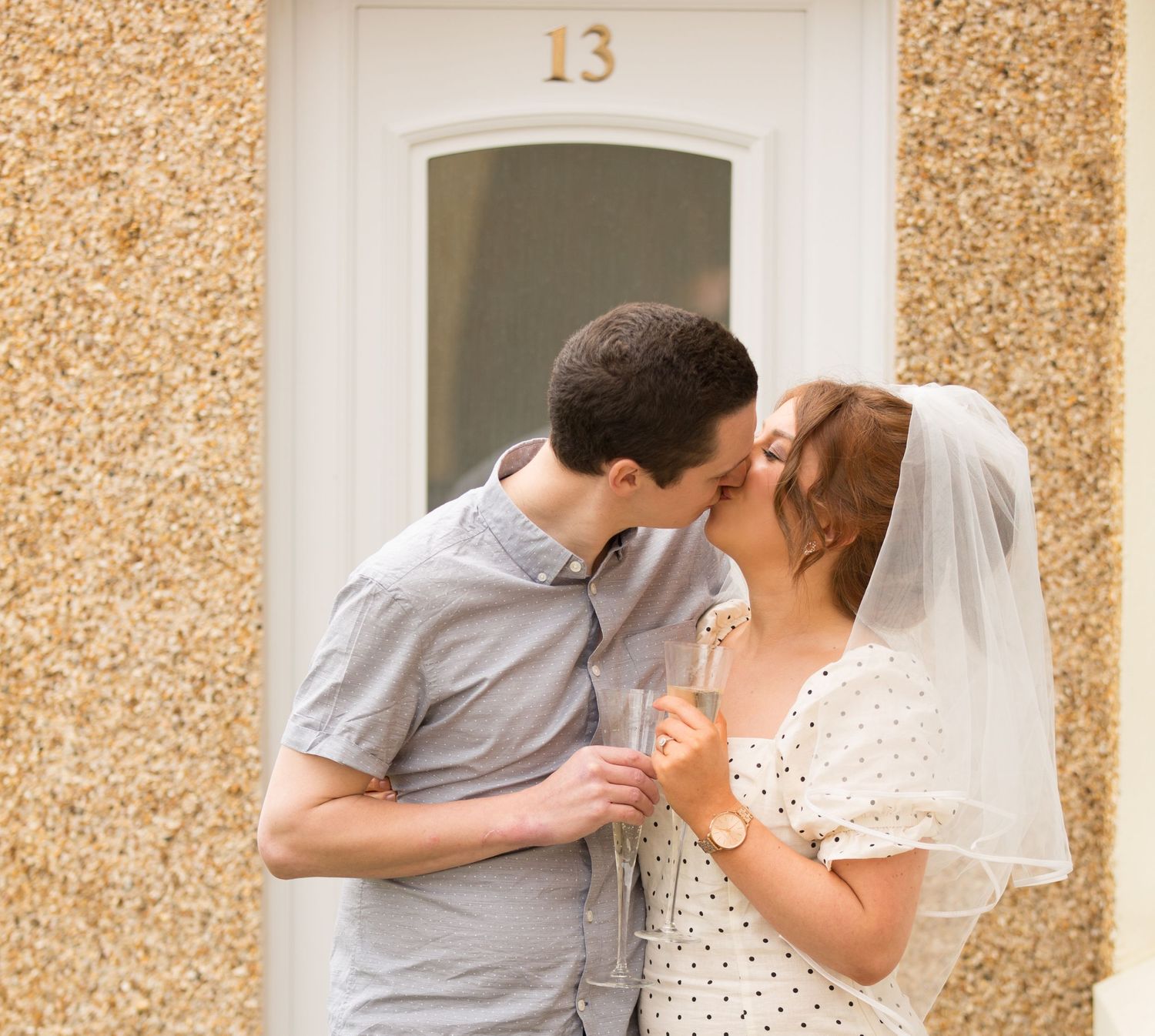 Romantic moment captured at entrance of house number 13 with textured stucco wall.