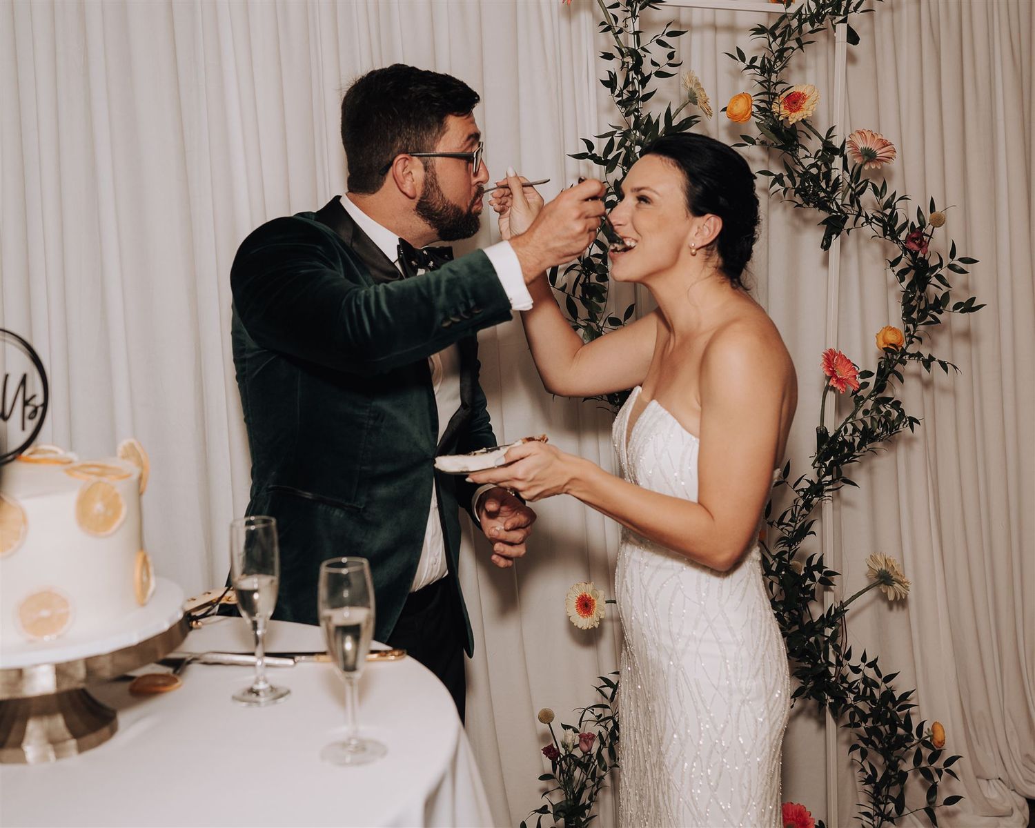 Couple sharing cake feeding moment during wedding reception celebration.