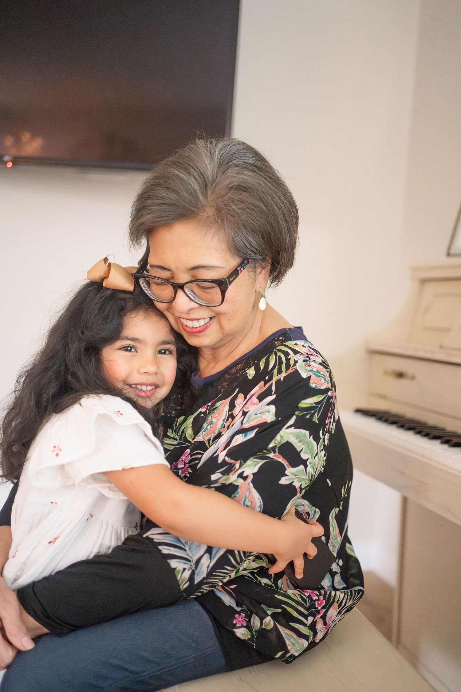 A heartwarming moment of embracing and smiling while sitting on a couch near a piano.