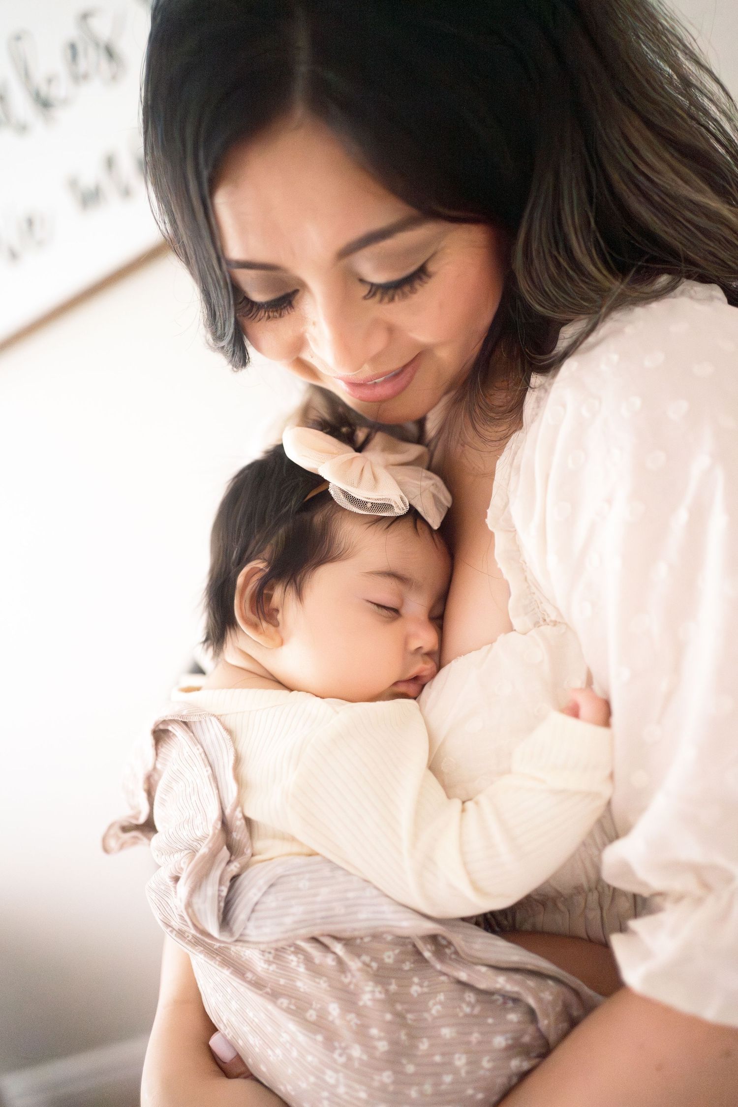 A tender moment captured as a sleeping baby rests peacefully in parent's arms wearing a cream colored sweater.