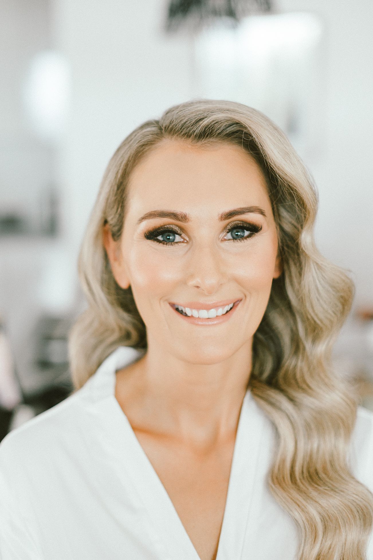 Elegant bridal beauty preparation in soft, natural lighting.