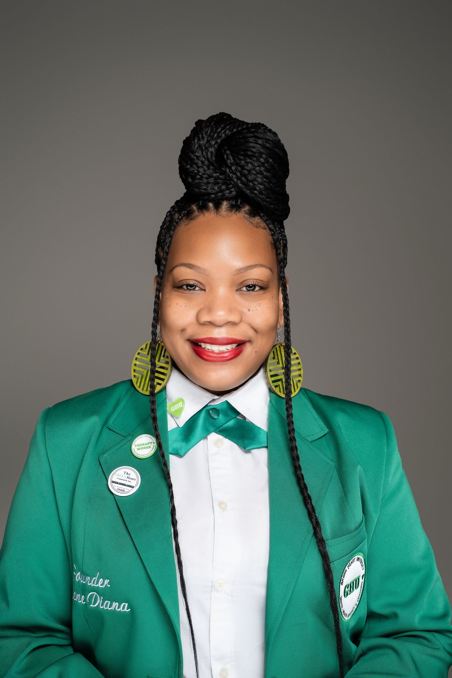 Professional portrait in green blazer with bow tie and statement earrings.