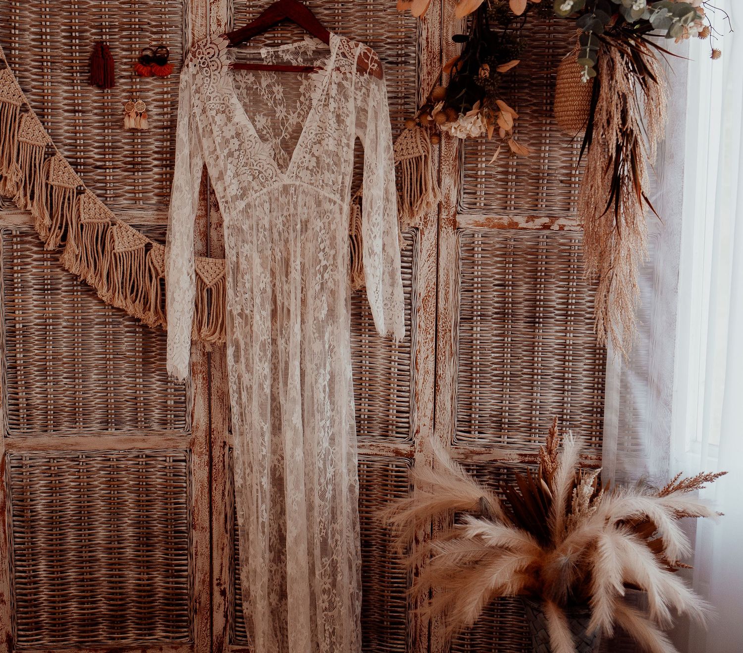 Vintage-inspired dresses and garments displayed on hangers against a textured wicker backdrop.