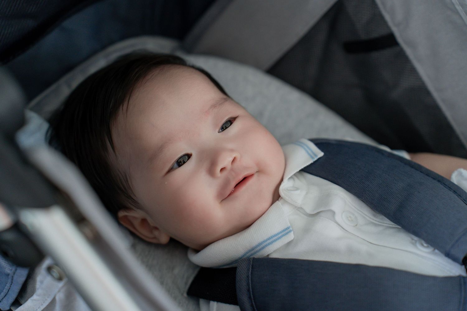 Baby in formal white attire resting in a stroller.