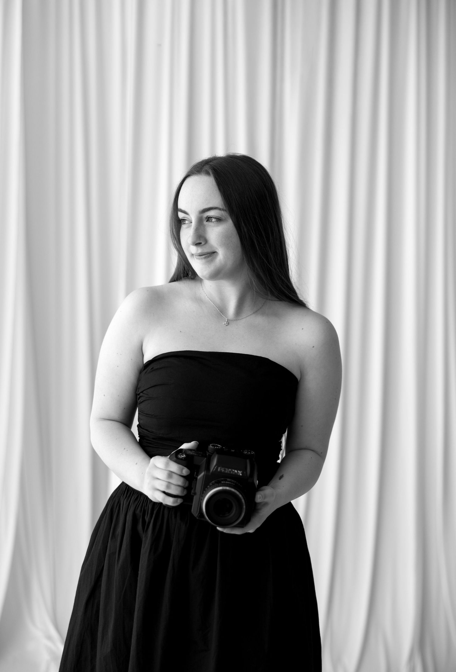 Black and white image of a photographer in a sparkly dress taking a photo.