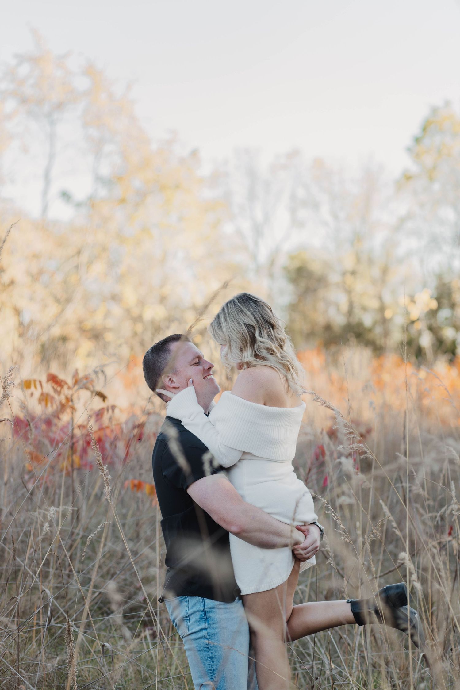 Intimate couple embracing in warm sunlight wearing casual sweaters.