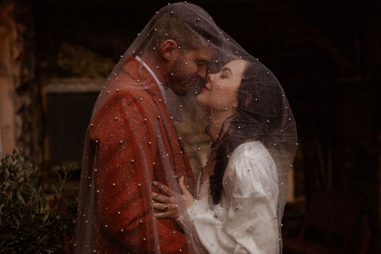 A romantic wedding couple shares intimate moments under warm sunset lighting in a vintage-inspired setting.