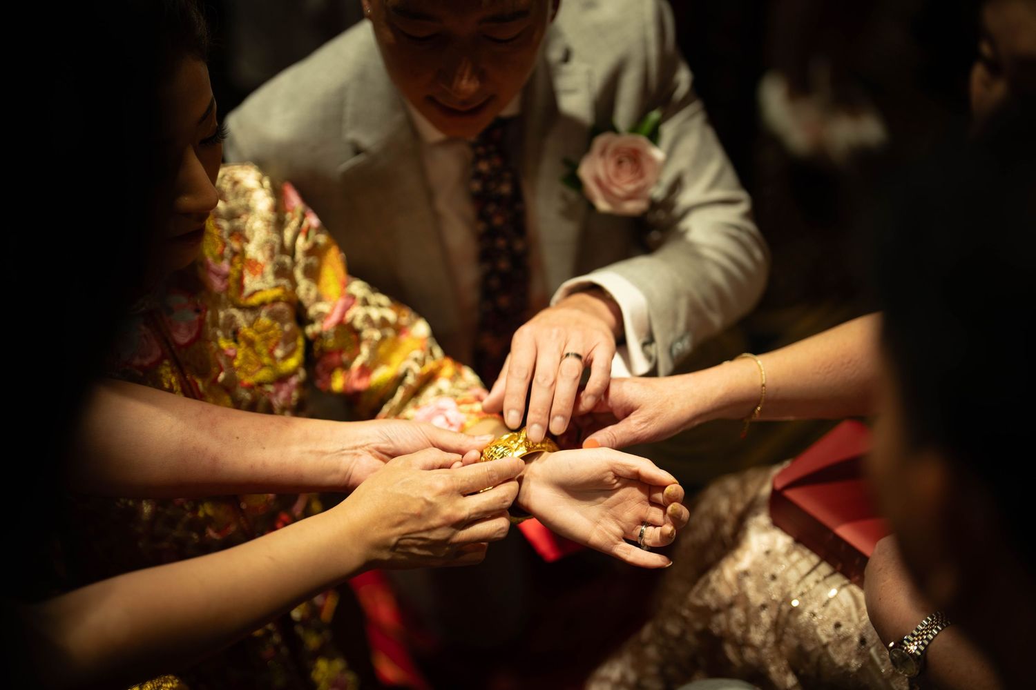 Multiple hands joining together in a circle during a ceremonial moment.