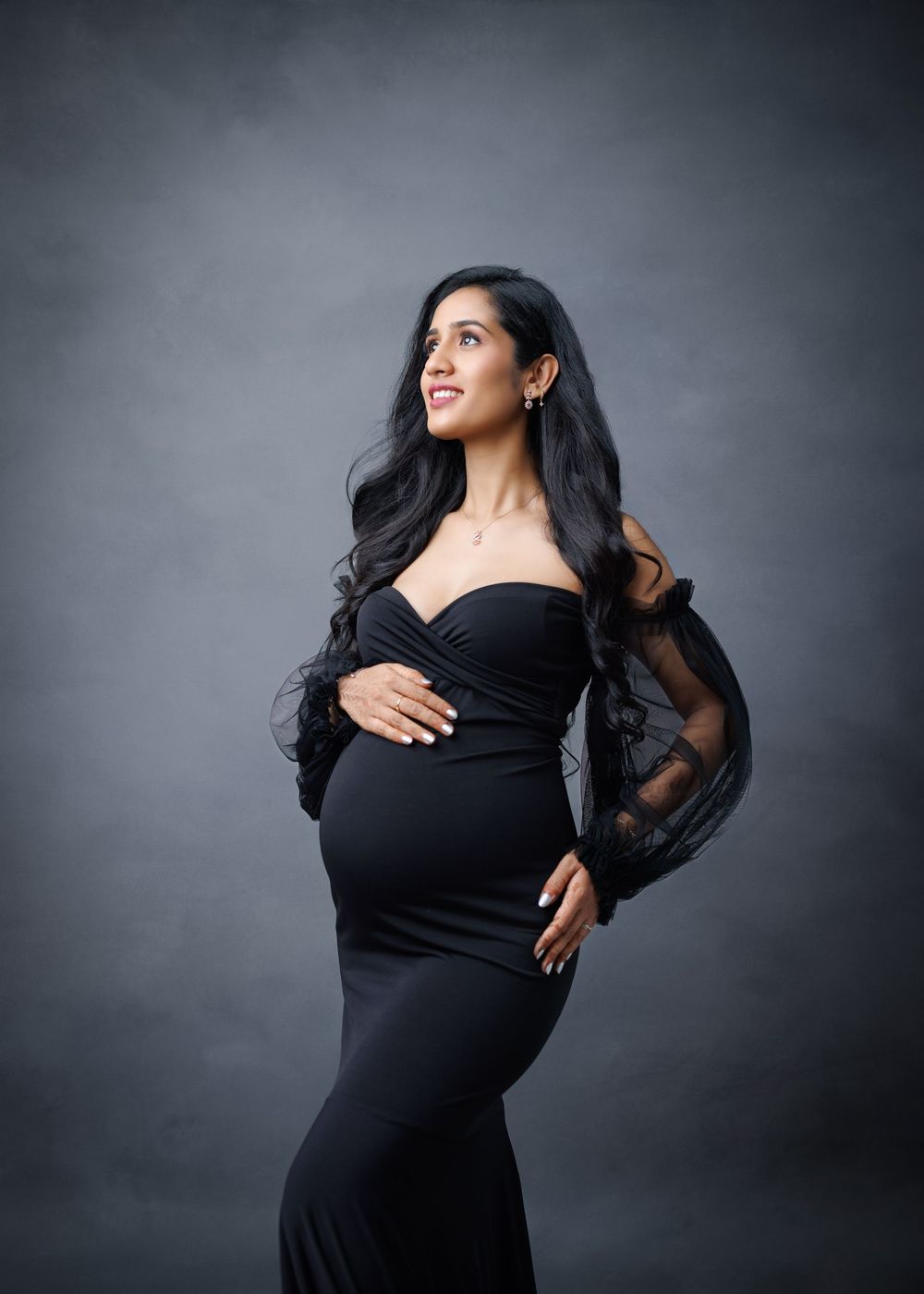A model in a black dress poses gracefully in a series of studio portraits against a gray backdrop.
