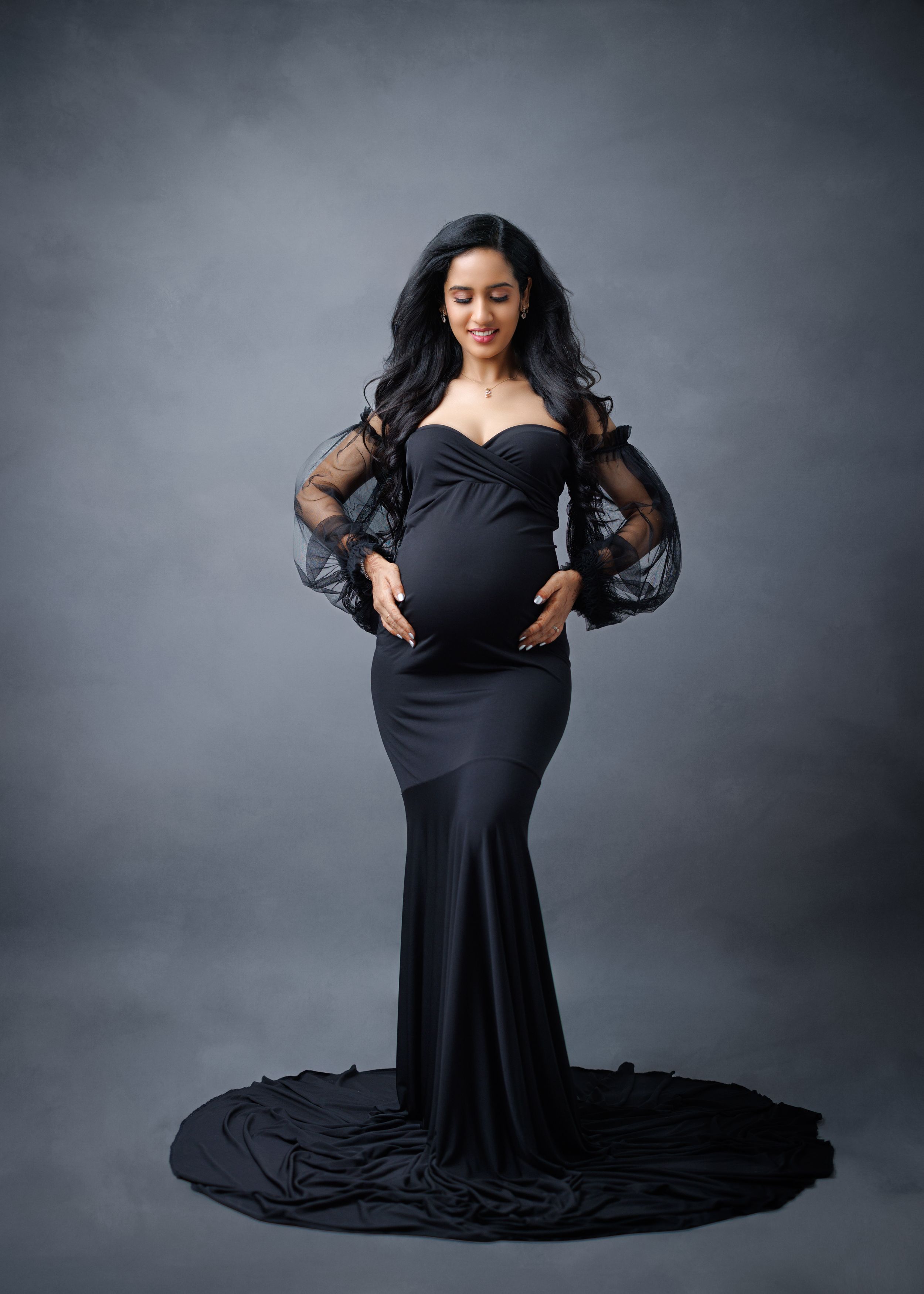 Seated model wearing a flowing black gown gives expressive poses in dramatic studio lighting.