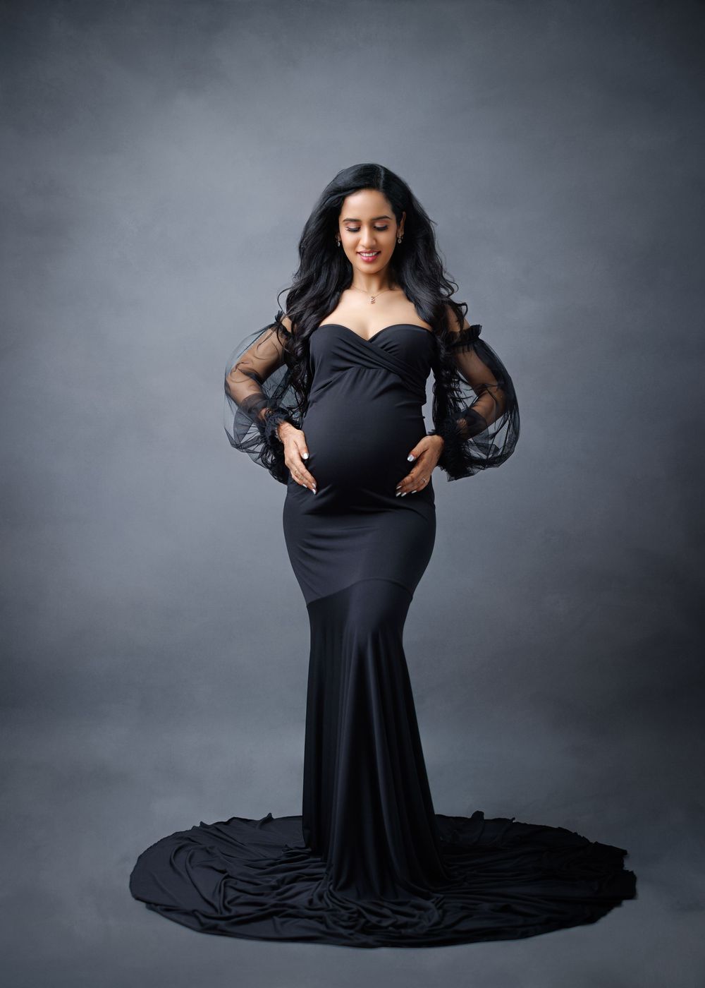 Seated model wearing a flowing black gown gives expressive poses in dramatic studio lighting.