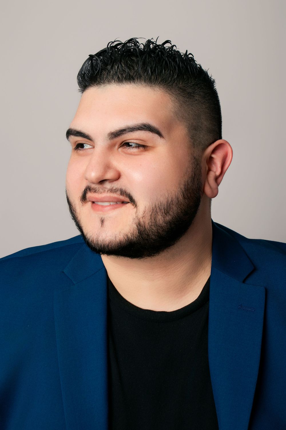 Portrait series showing different angles in navy blazer and black shirt against neutral background.
