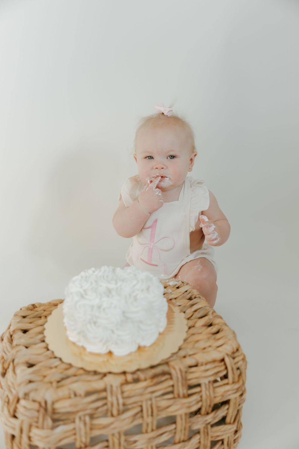 Three side-by-side photos show a baby sitting atop a woven basket prop with white floral decorations for a photoshoot.