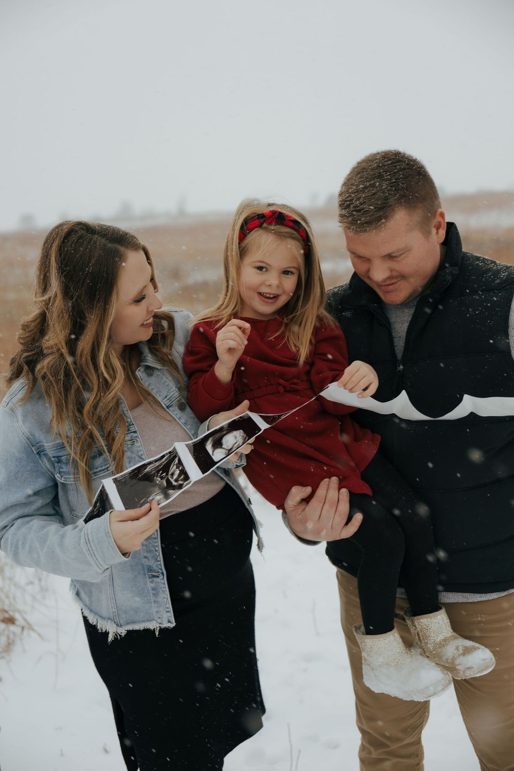 A couple in winter clothing shares playful moments in the snow during a photo session.
