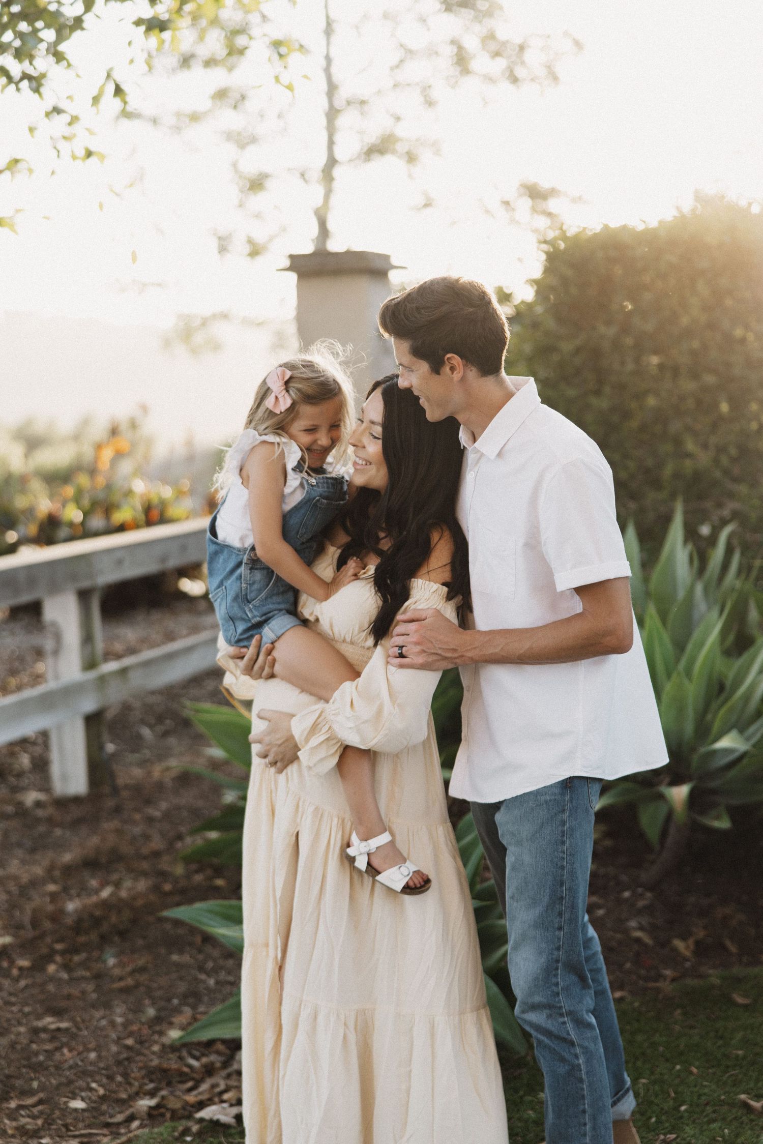 A loving family shares an intimate moment together at sunset in a garden setting with mountain views.