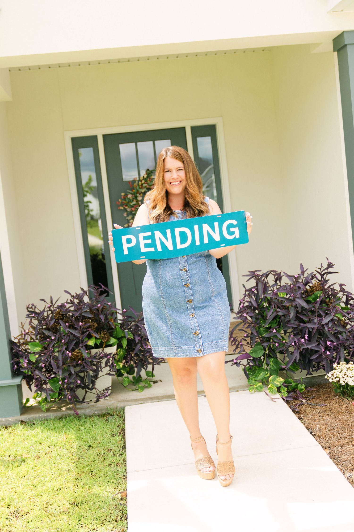 Real estate branding photo of Amy Wodicka holding a pending sign outside a home