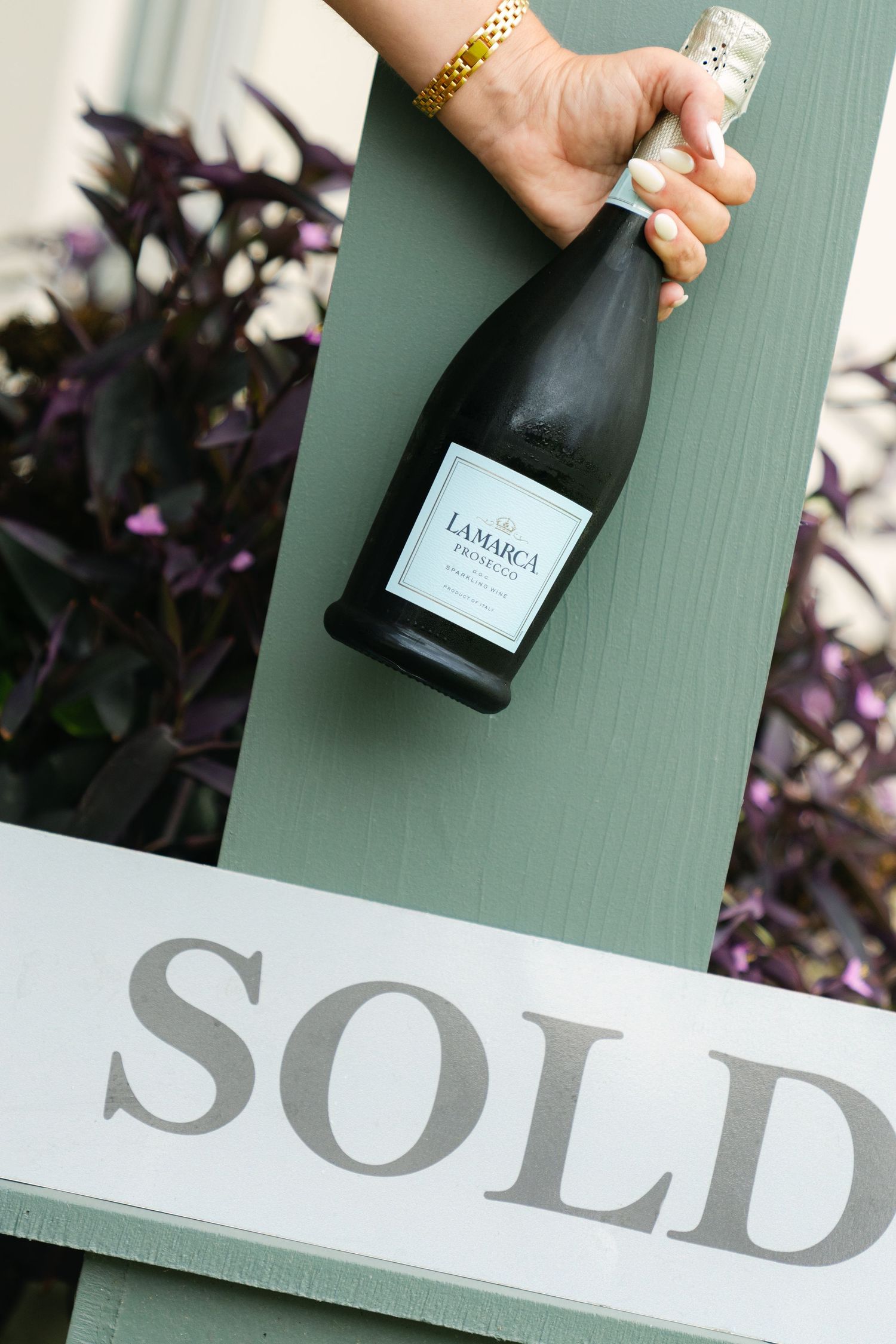 Real estate branding detail showing champagne and a sold sign