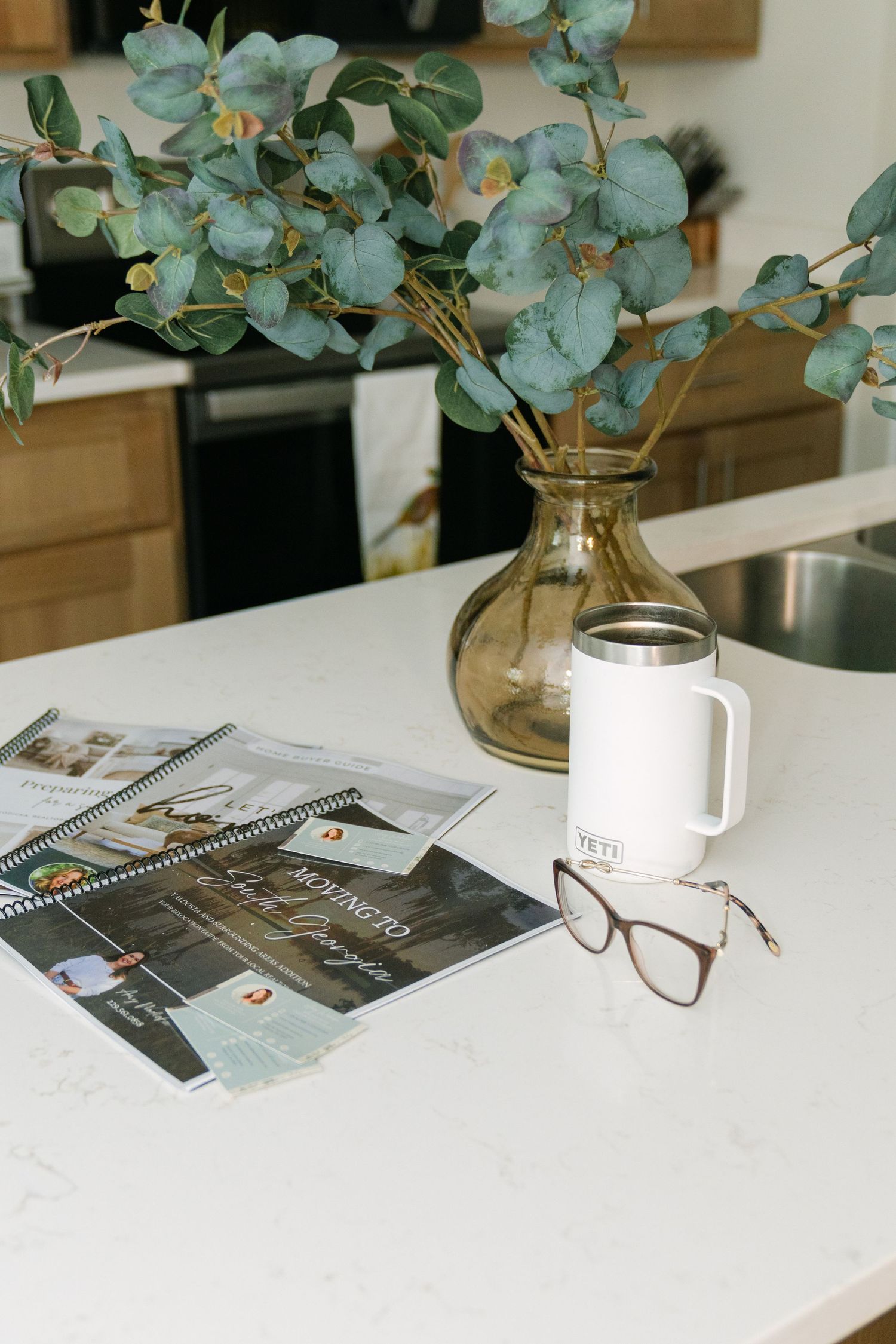 Branding photo detail of real estate brochures, coffee, glasses, and flowers