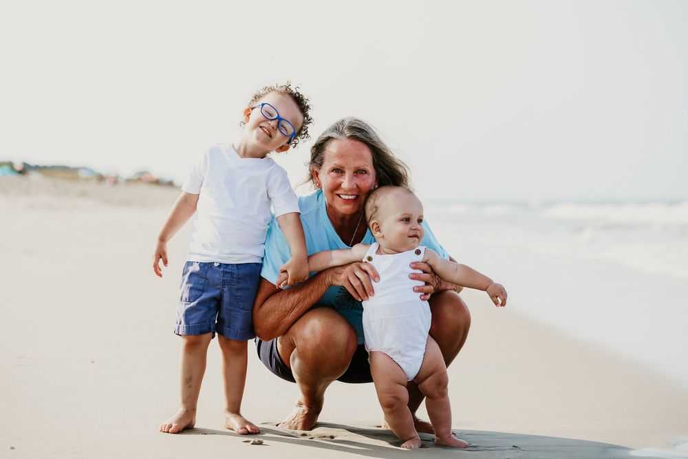 A family in white clothing plays together on a sandy beach during a sunny day at the OBX, North Carolina.