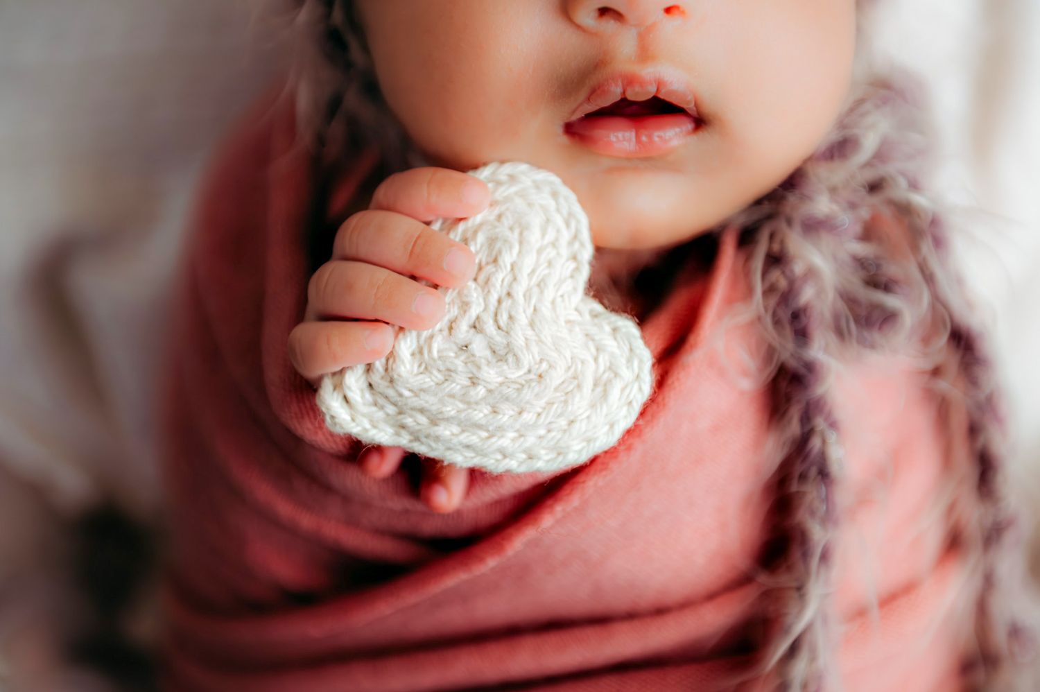 Close-up artistic portrait showing soft details in muted pink tones.