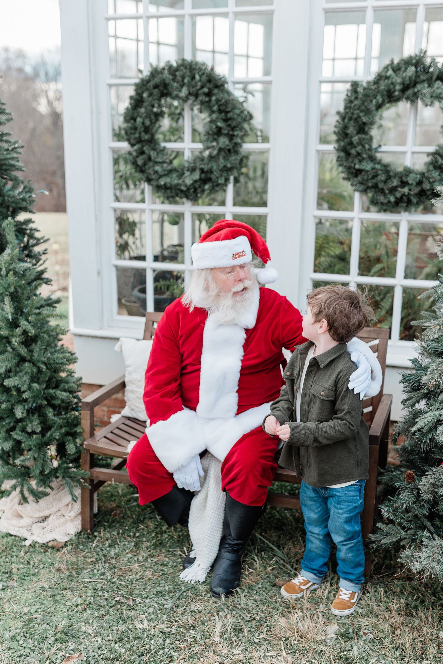 A heartwarming moment between a child and Santa Claus sitting on a bench in a festive winter setting.