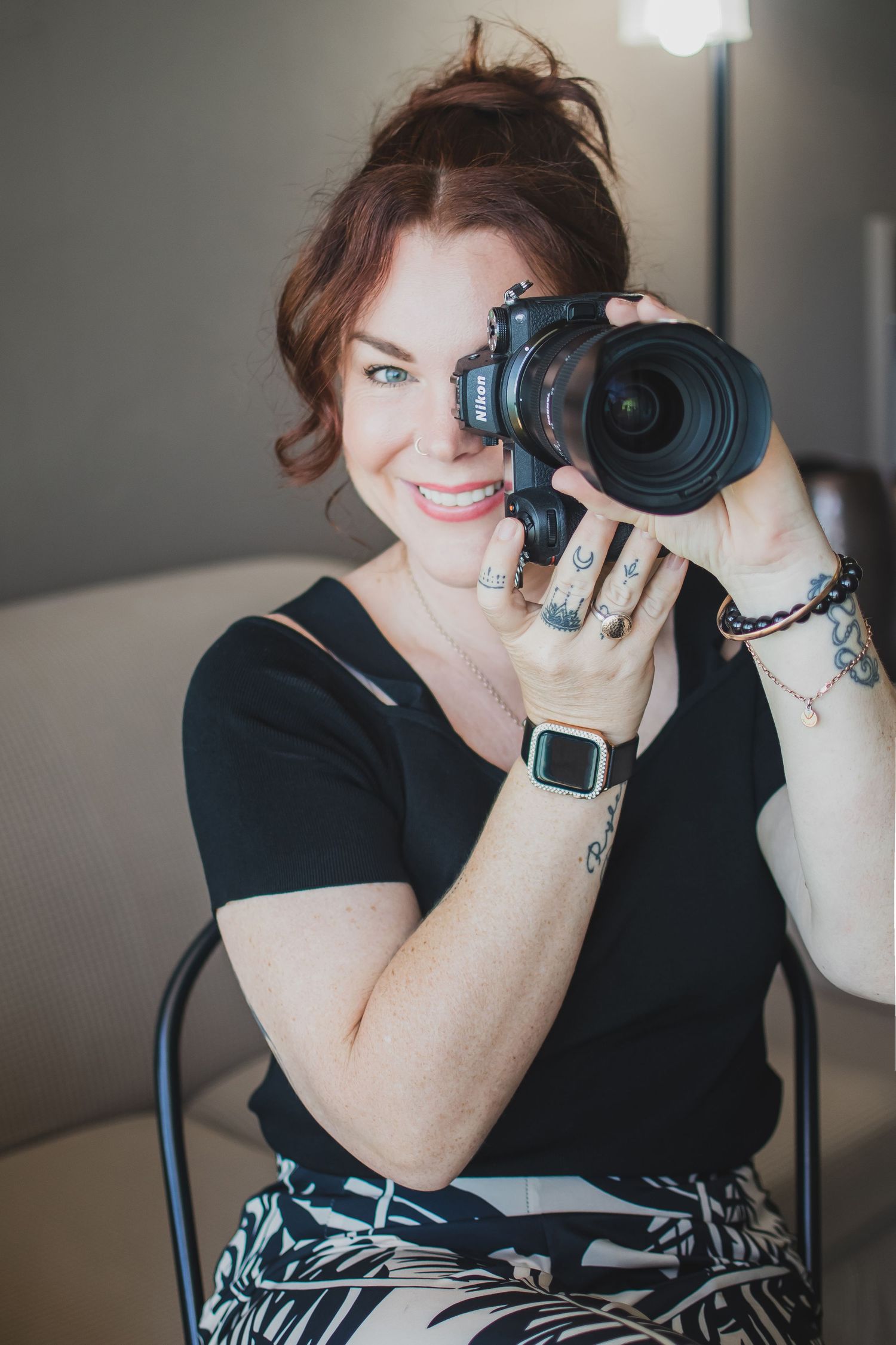 Person in black shirt using professional camera equipment against grey background.