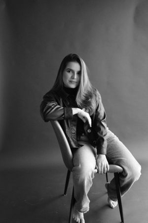 Black and white portrait with leather jacket and jeans in casual pose.