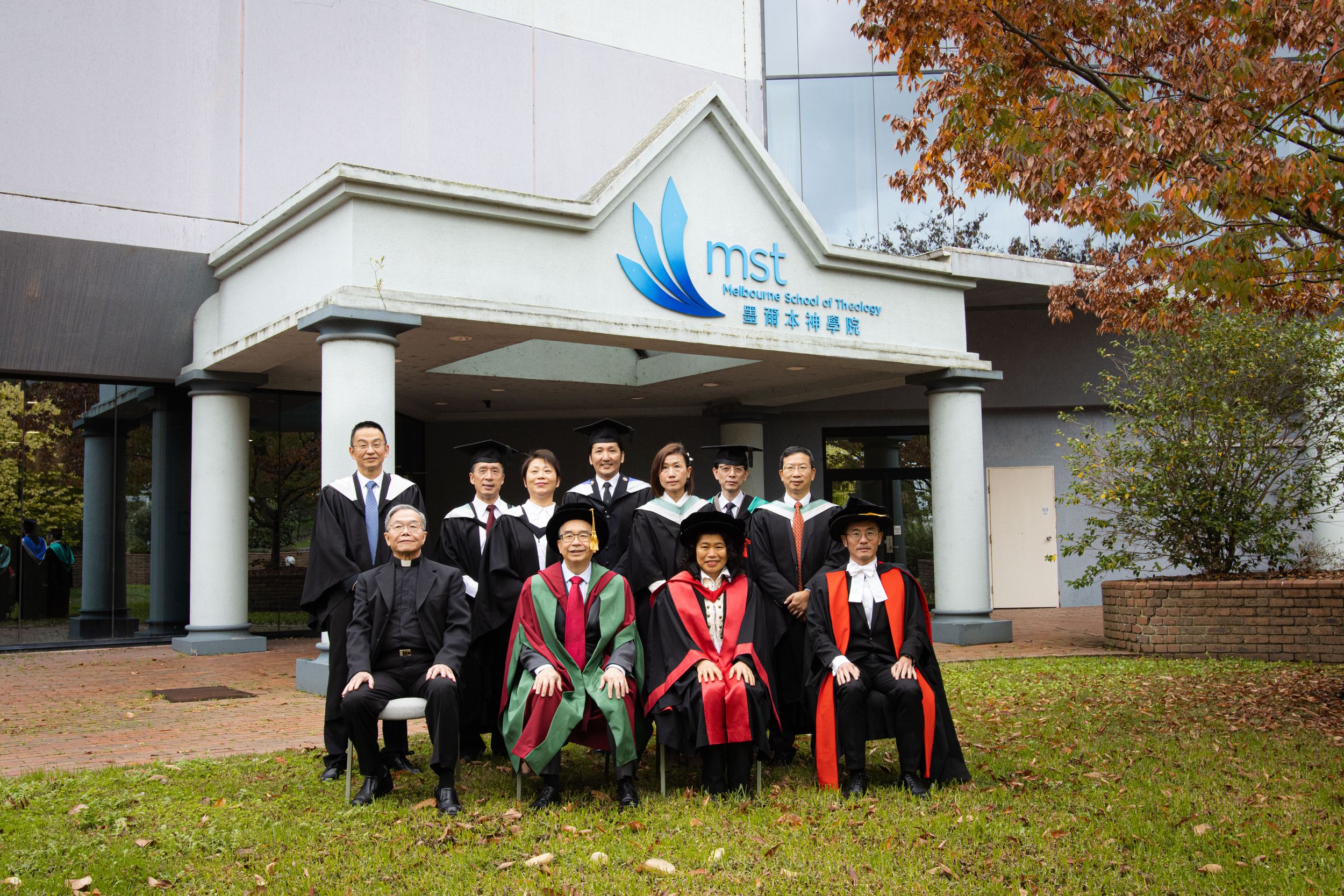 A group photo of graduates and faculty in academic regalia outside MSE building.