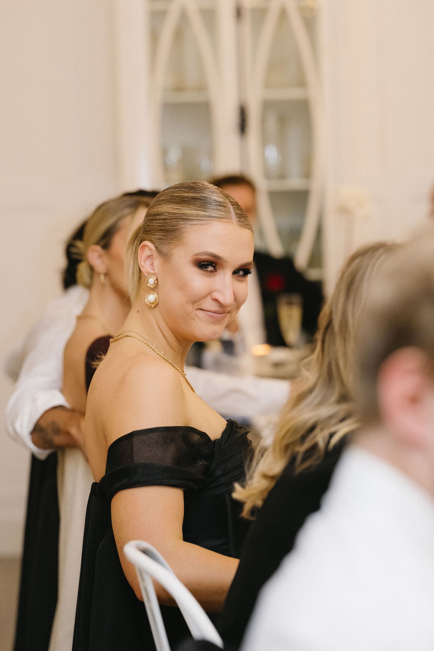 An elegant guest in a black off-shoulder dress at a formal wedding reception.