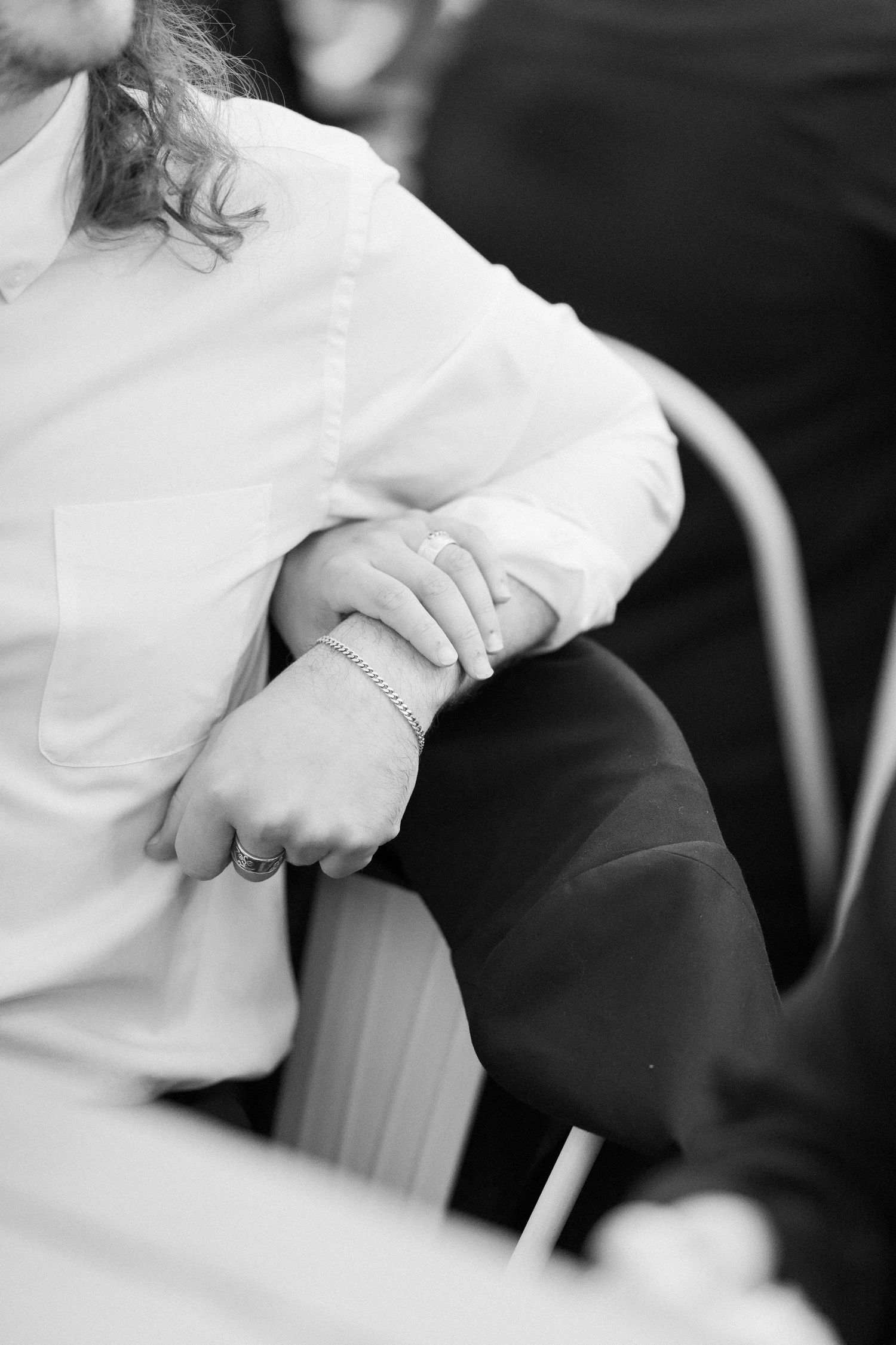 A black and white detail shot of hands clasped together during a wedding ceremony.