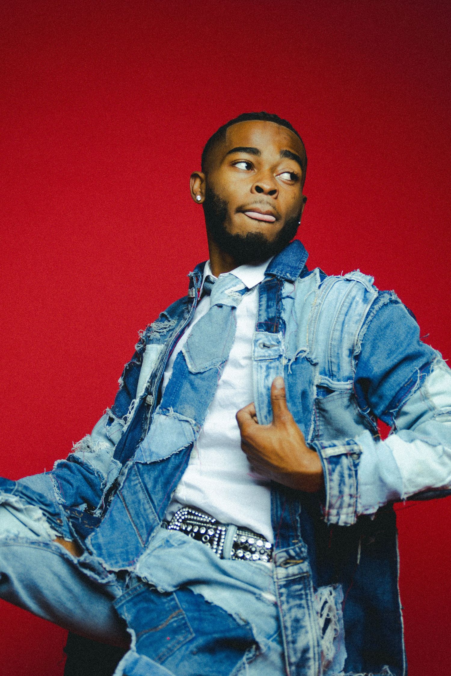 Person in denim jacket striking dynamic poses against red backdrop.