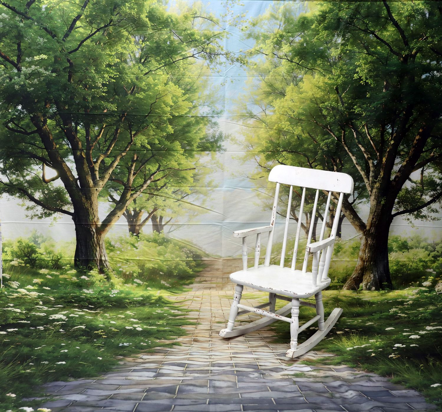 White rocking chair sitting peacefully between two trees on a garden path.