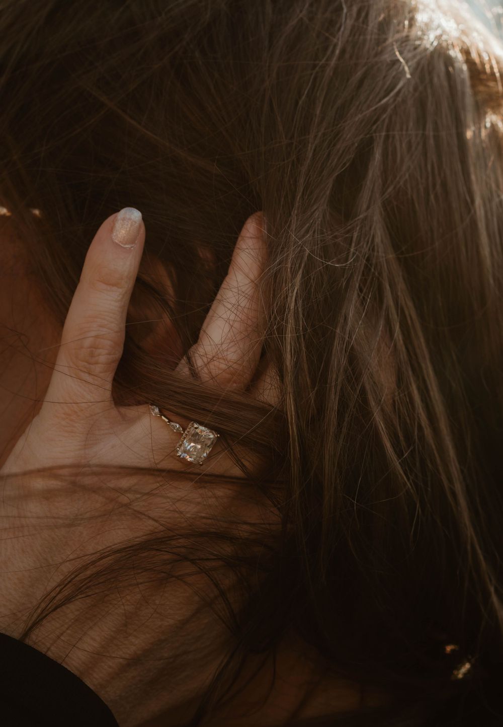 Close-up shot of a sparkling engagement ring being displayed in someone's hair.